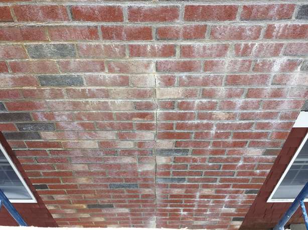 Cracked brick chimney with failed masonry repairs